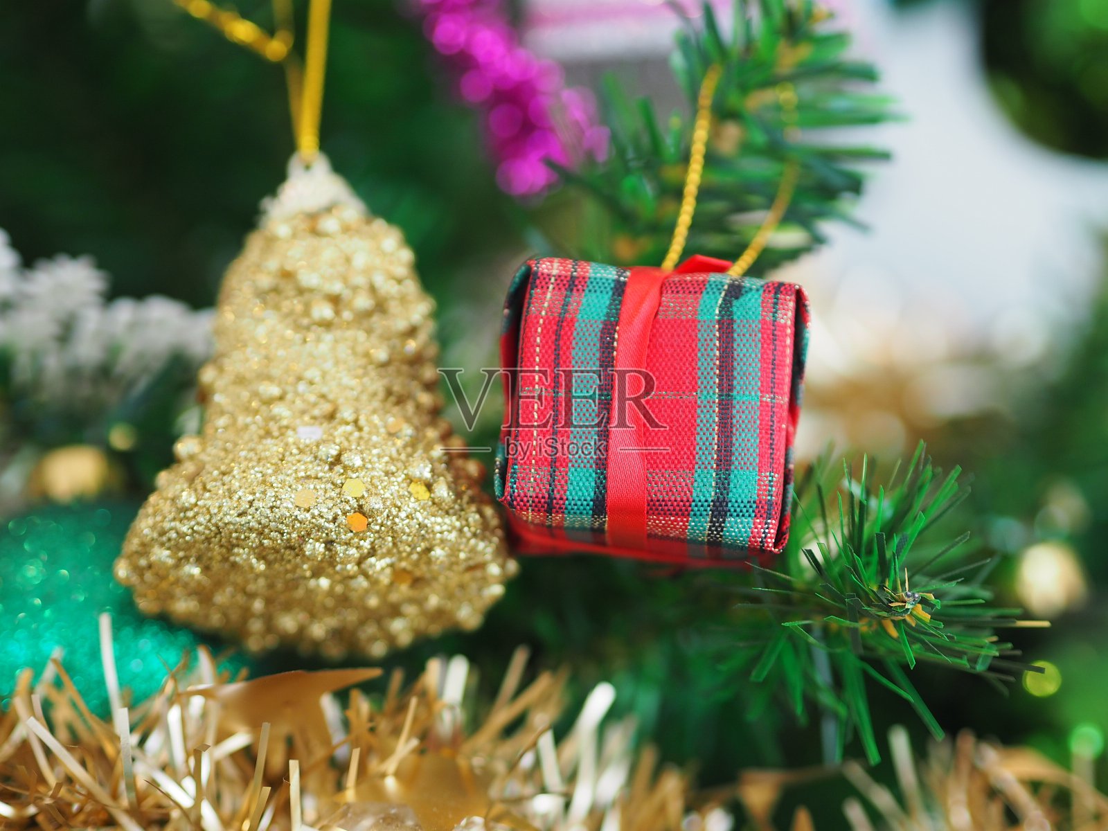 装饰过的圣诞树装饰有金铃金礼盒，树叶上的背景模糊了照片摄影图片