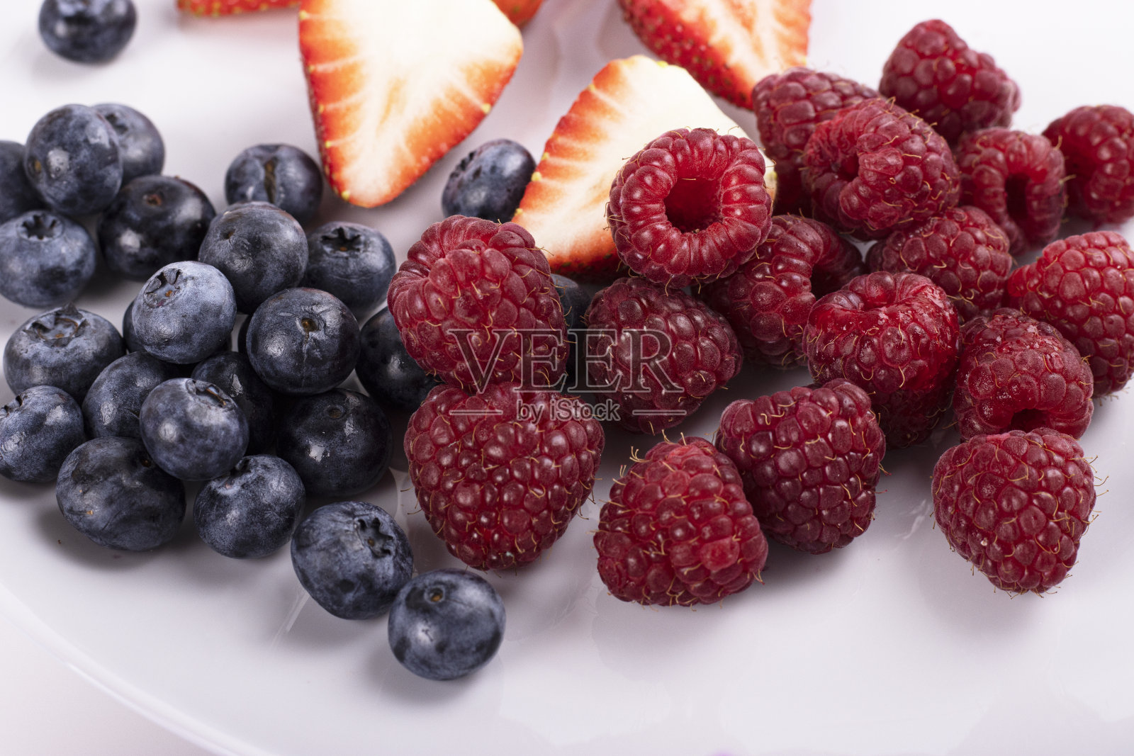 三个小碗的特写堆满了夏天的浆果，草莓，覆盆子，蓝莓照片摄影图片