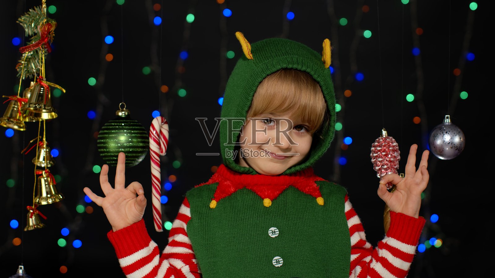 金发少年孩子孩子女孩在圣诞精灵圣诞老人助手服装表演gok手势，好标志照片摄影图片