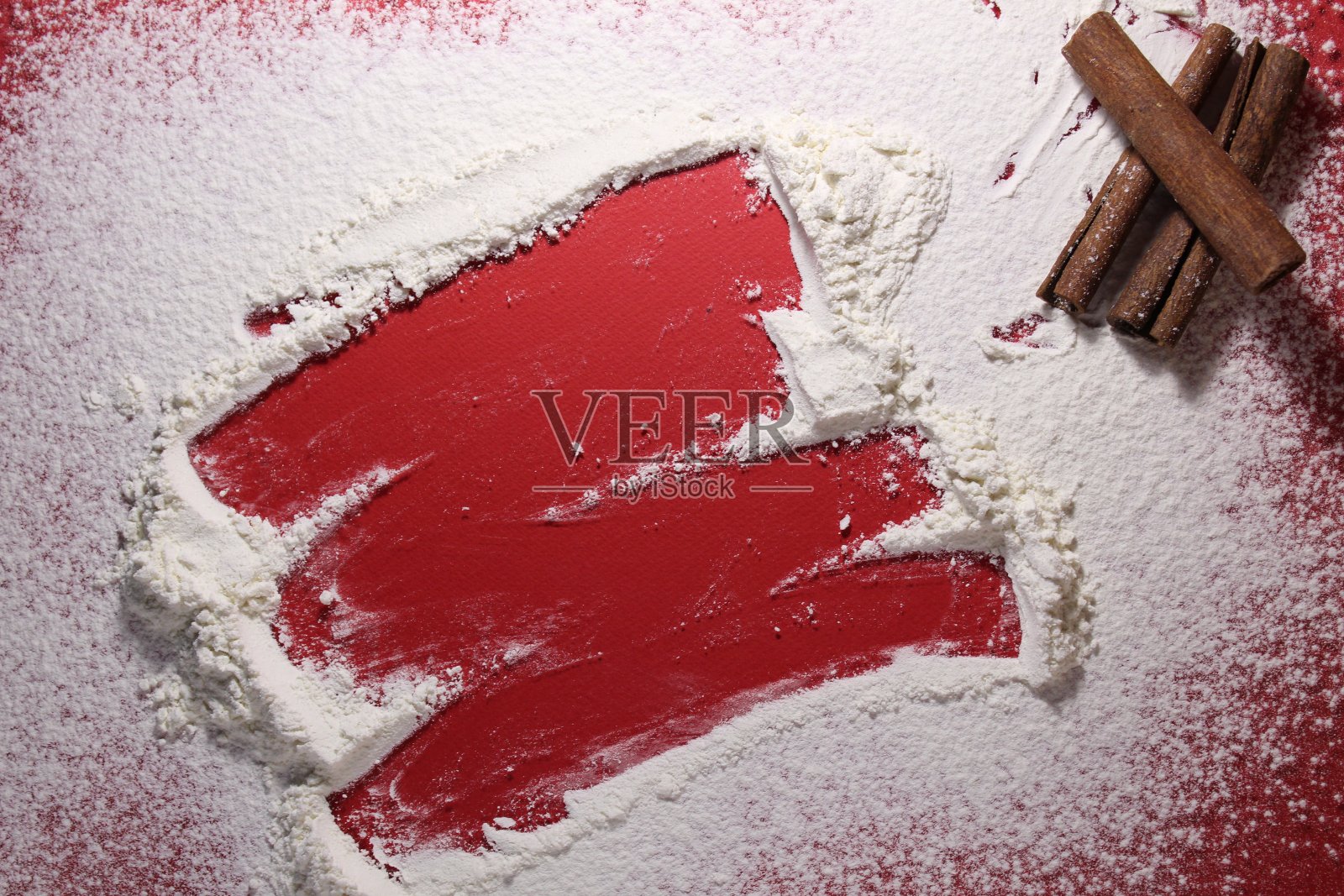 红色背景上撒上面粉或糖粉，旁边放着肉桂棒，有一个复制空间照片摄影图片