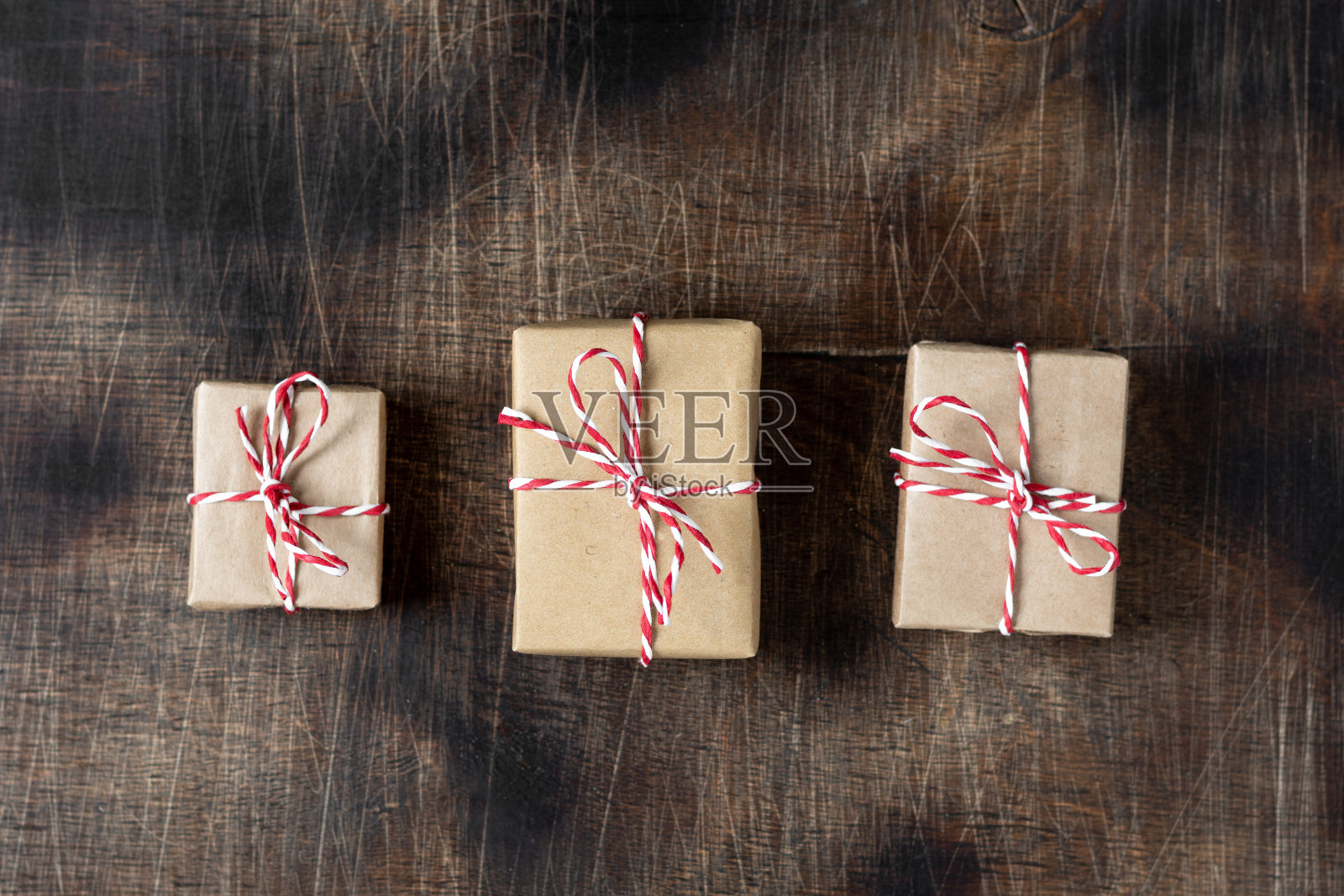 礼物盒子。棕色的木桌上放着牛皮纸包装的礼品盒。圣诞背景与礼物和木制节日装饰。圣诞节的概念。环保。前视图。弗拉照片摄影图片