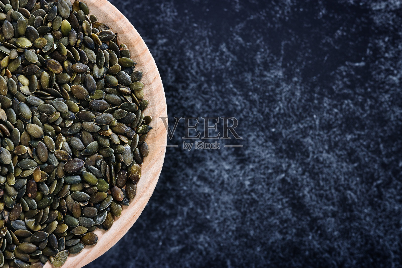 装满南瓜子的木盘子照片摄影图片