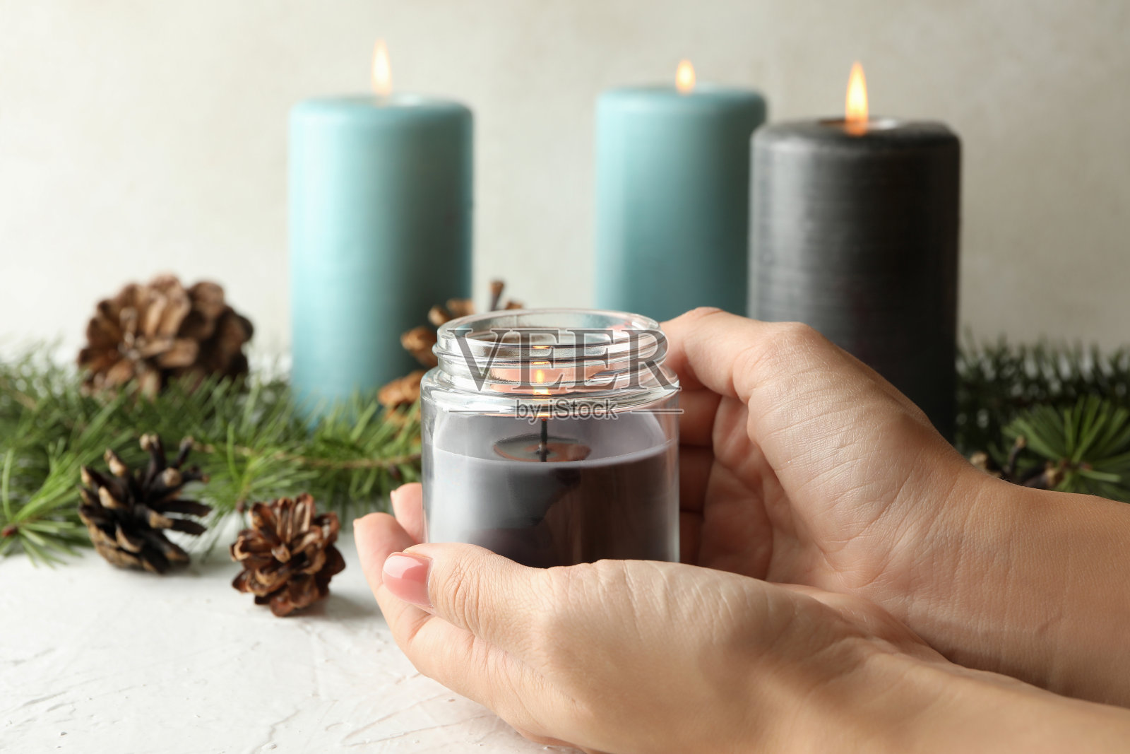 女人的手握着玻璃瓶里燃烧着的香薰蜡烛照片摄影图片