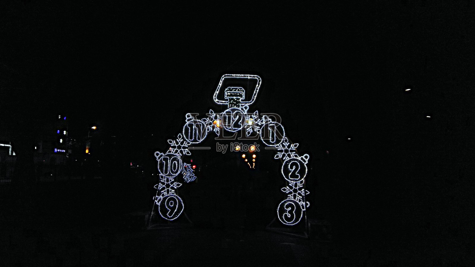 户外新年的半边钟面灯光剪影装饰在小巷里。照片摄影图片