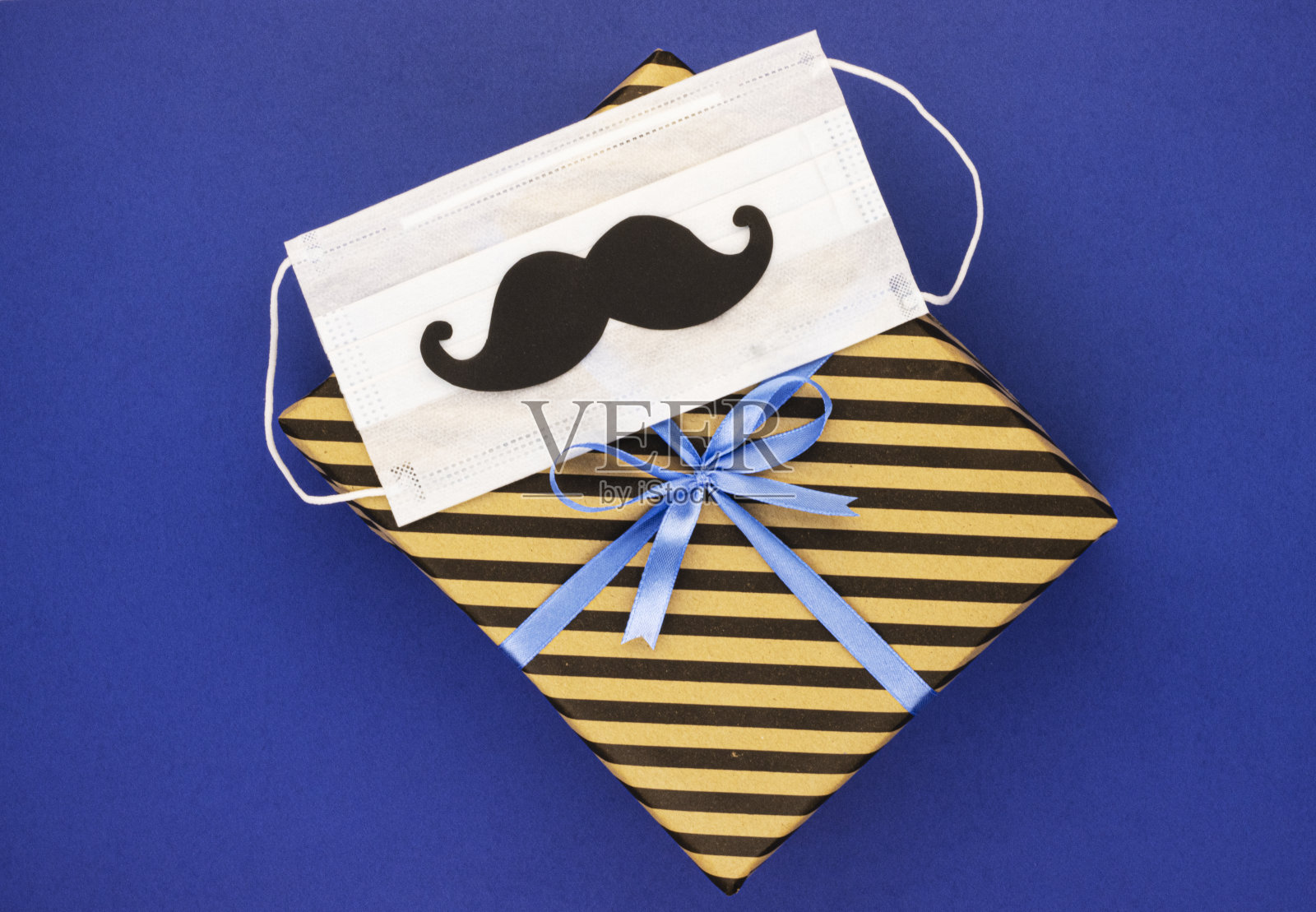 带有医用面具和蓝色背景纸胡子的礼盒照片摄影图片