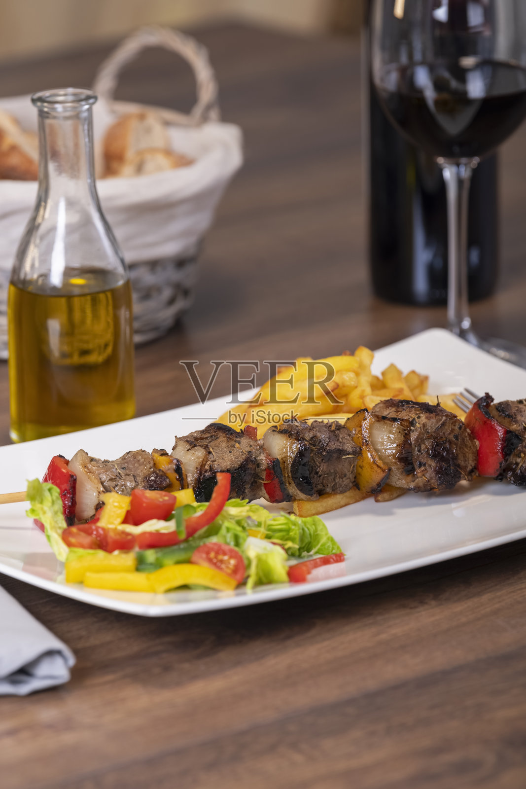 烤牛肉串配切好的蔬菜和炸薯条放在盘子里照片摄影图片