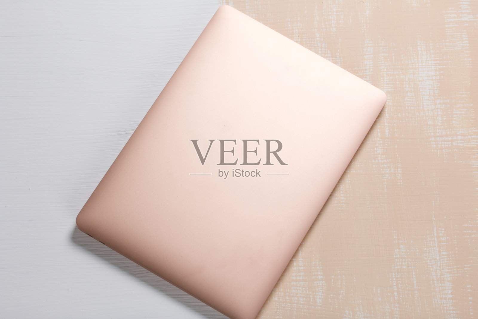 笔记本电脑是粉红色的。表面漆成白色和米色。从上方拍摄的。照片摄影图片