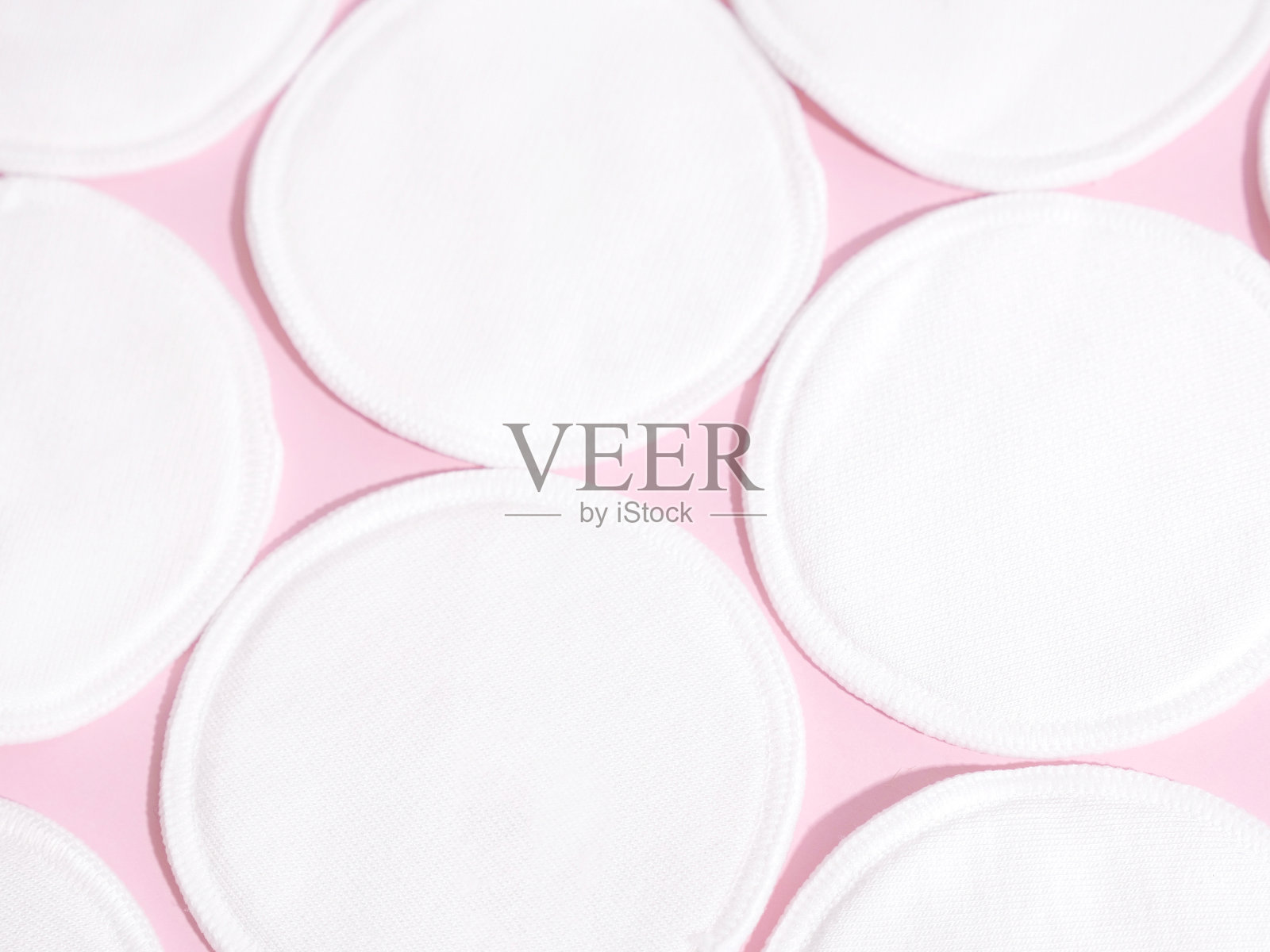 粉色背景的有机棉垫。零浪费，可重复使用，生态，卸妆和洗涤概念。图案，硬光，平放，近距离照片摄影图片