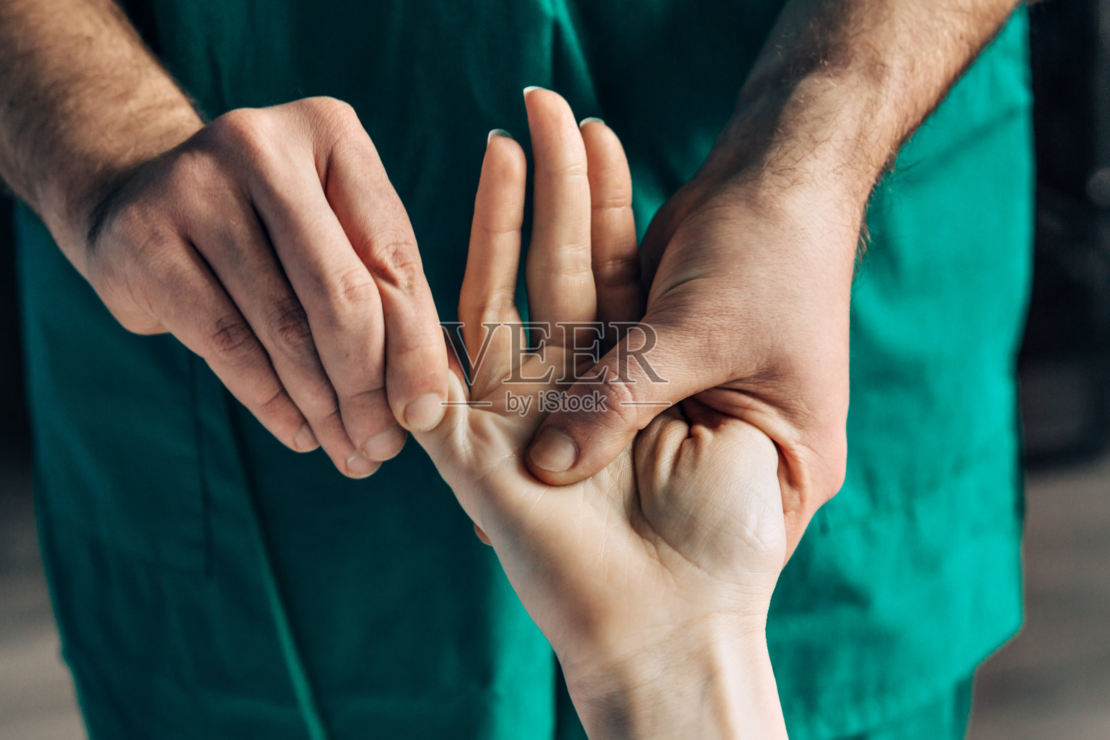 手腕按摩。男性按摩师按压女性手上的敏感部位。照片摄影图片