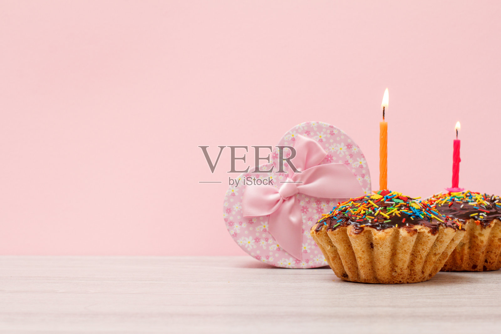 生日松饼与燃烧的节日蜡烛和礼物盒在粉红色的背景。照片摄影图片