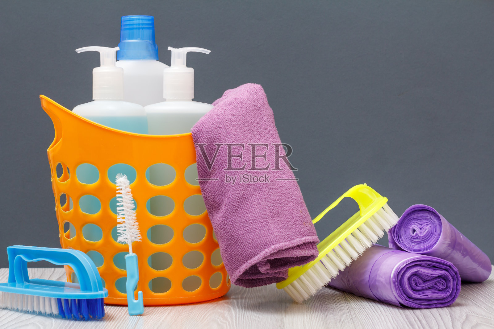 瓶子洗碗液，刷在一个篮子和垃圾袋在灰色背景。照片摄影图片