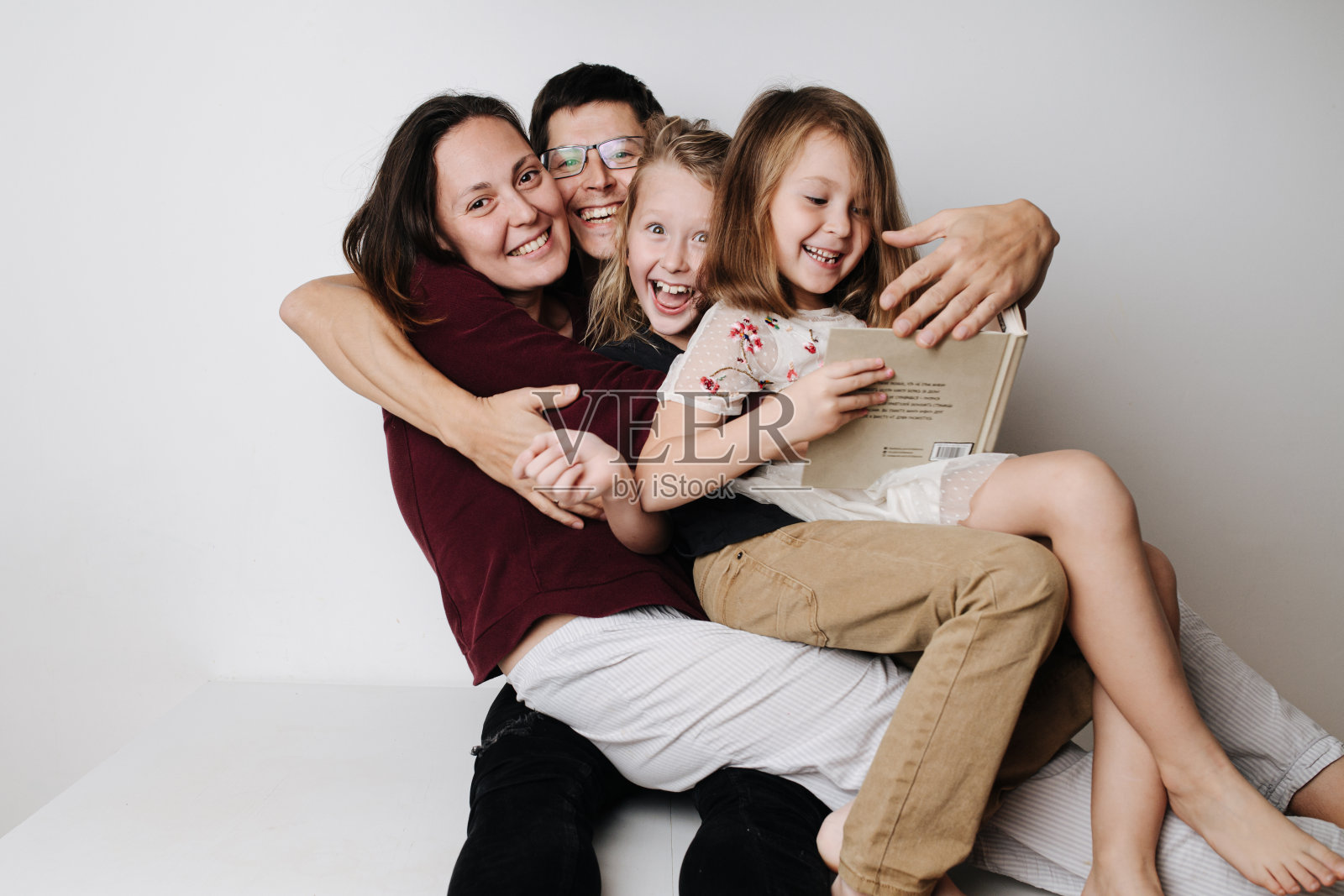 幸福的一家人坐在一起吃饭。爸爸把妻子和孩子抱在怀里照片摄影图片