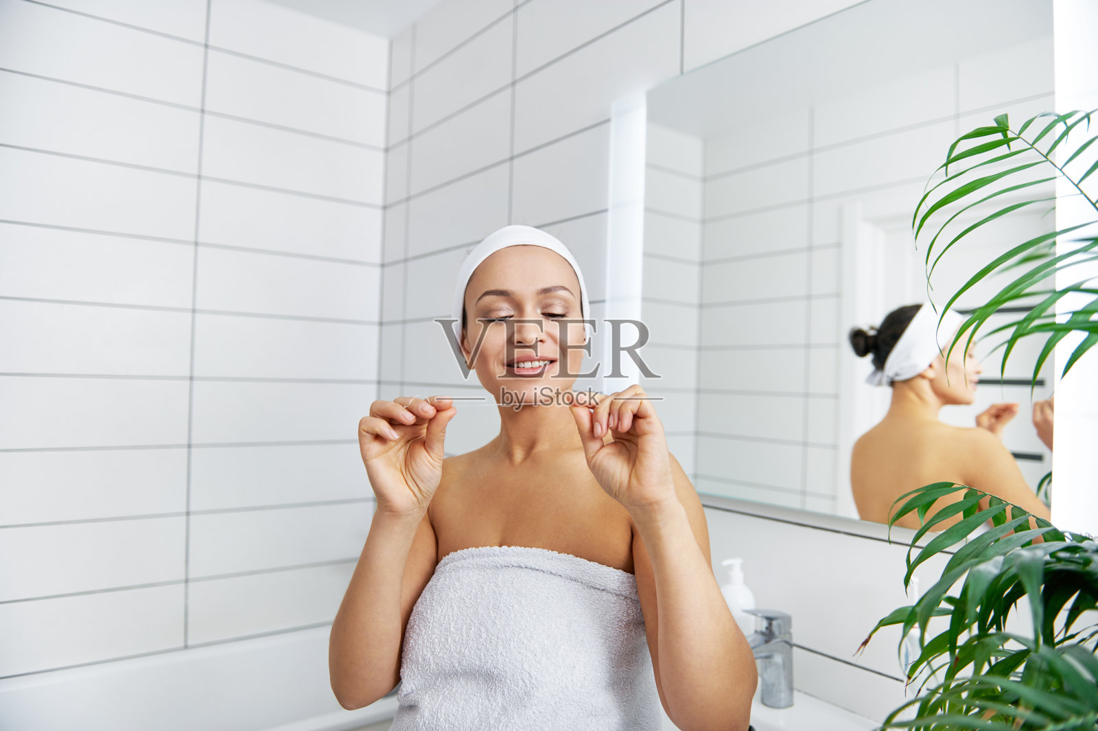 年轻健康的女人有一个美丽的微笑持有牙齿卫生牙线照片摄影图片