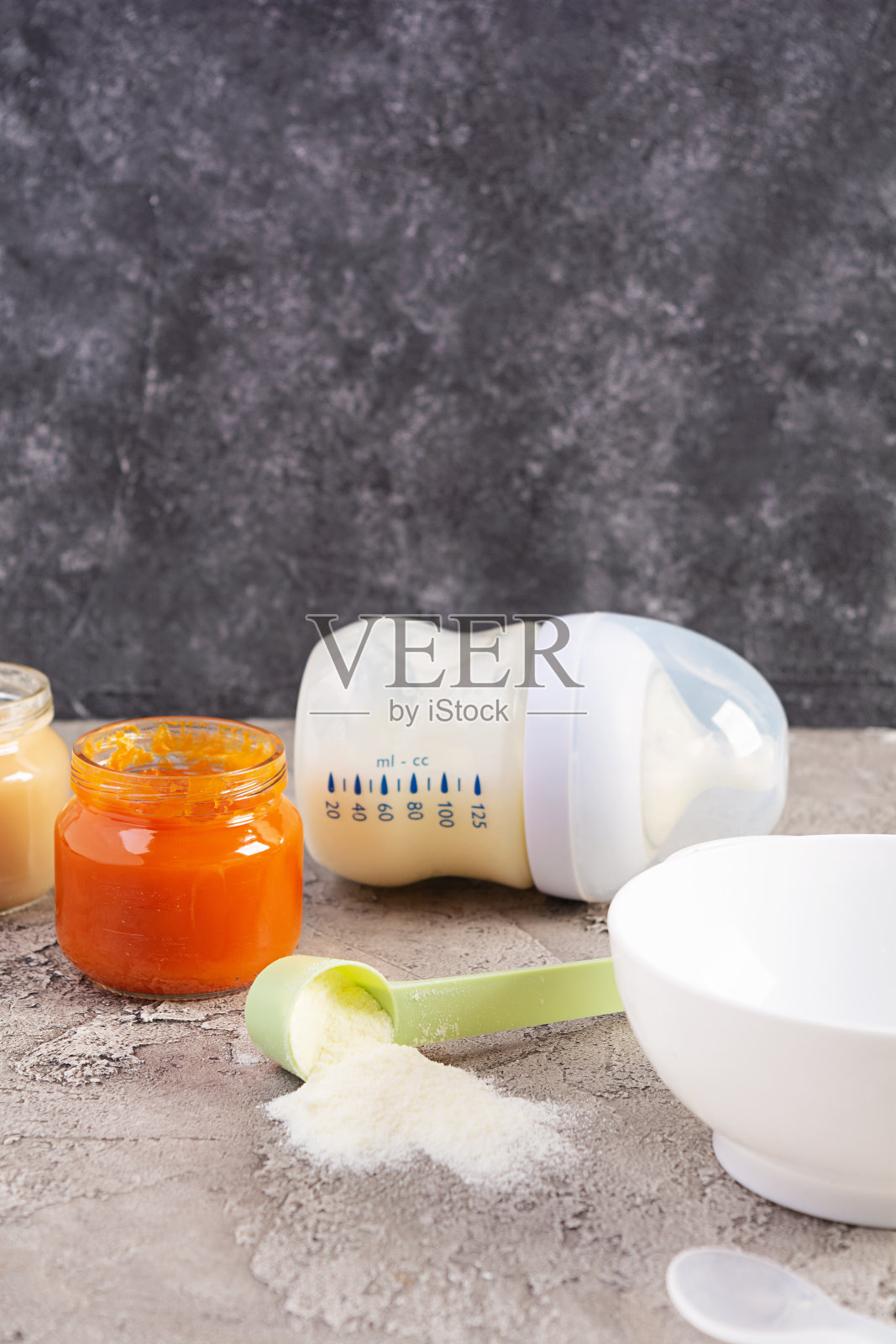 灰色背景的碗里有蔬菜泥和一瓶婴儿食品照片摄影图片