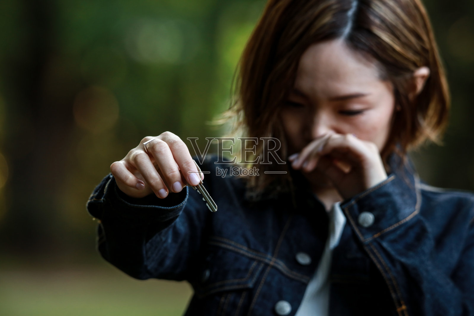 女人一边哭一边递钥匙照片摄影图片
