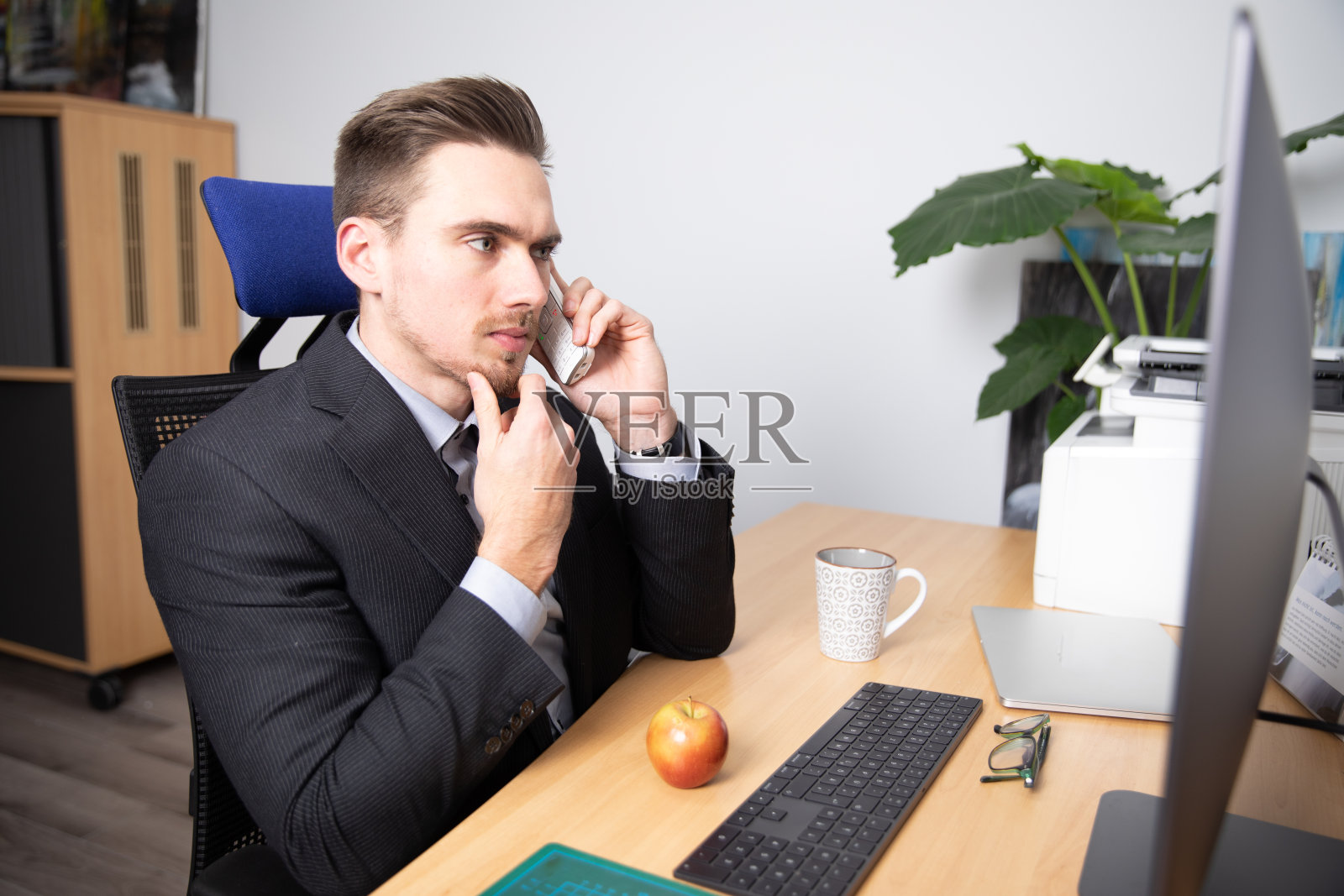 年轻的商人微笑着坐在他的办公室里。照片摄影图片