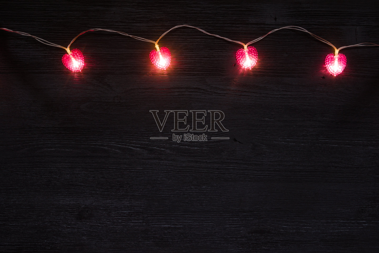 黑色木制背景，粉色心形花环照片摄影图片