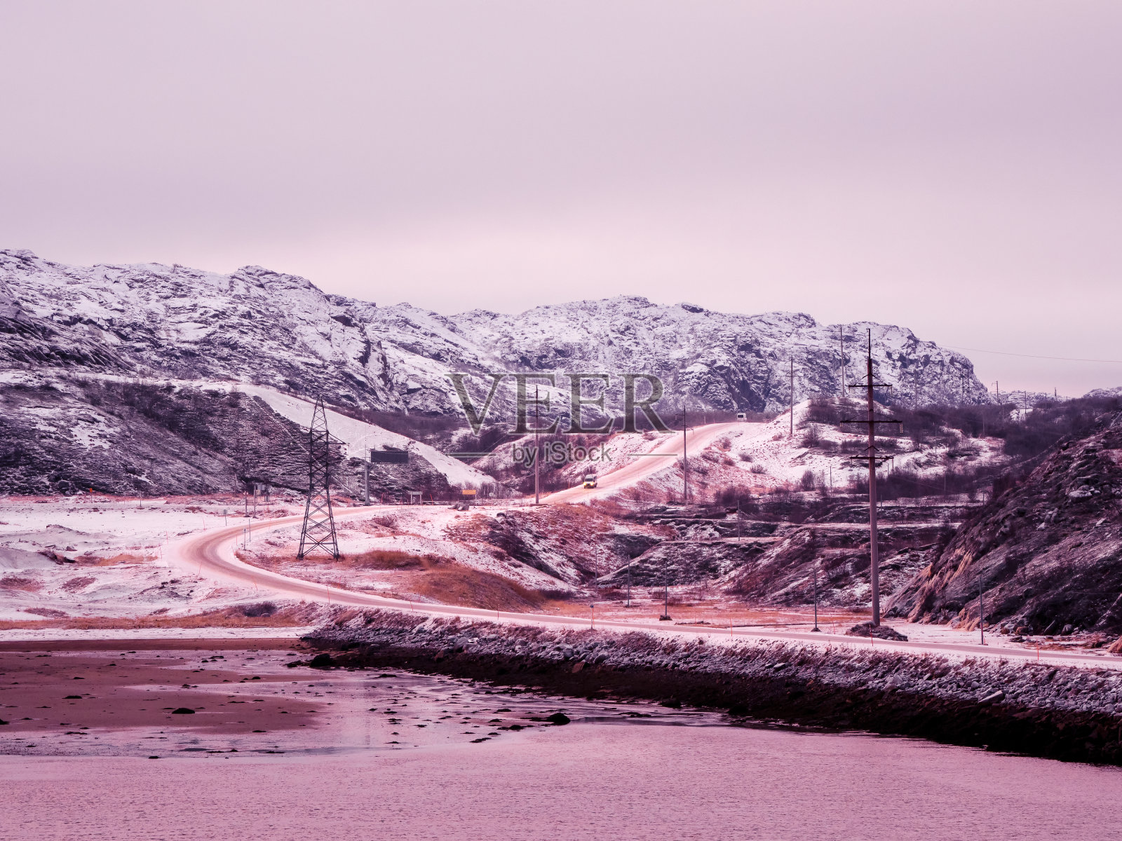 北极山脉之间的高速公路。北方的冬天路，转弯上了路。洋红色的极地日落照片摄影图片
