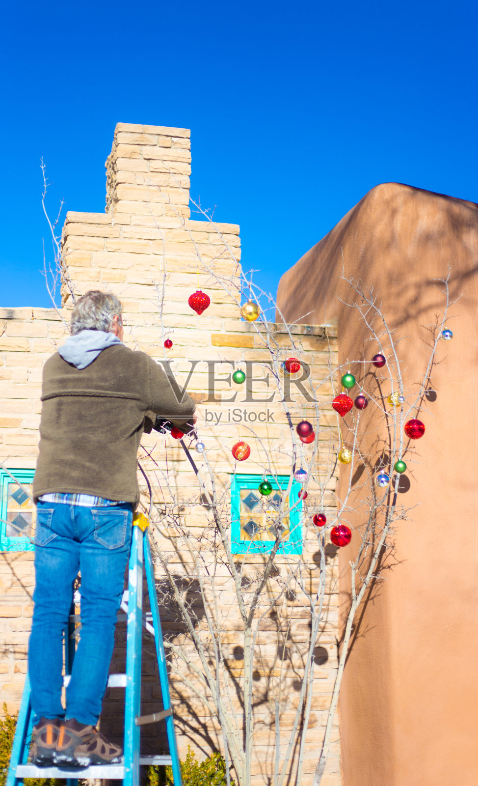 梯子上的人在外面挂圣诞装饰照片摄影图片