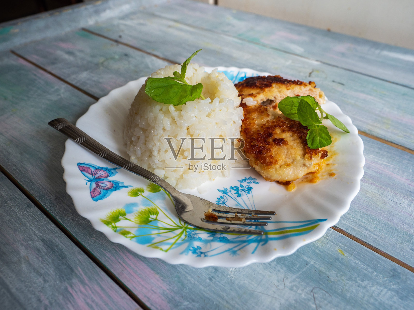 米饭和鸡片叠在一起，新鲜的香草叶放在一个轻盘子里照片摄影图片