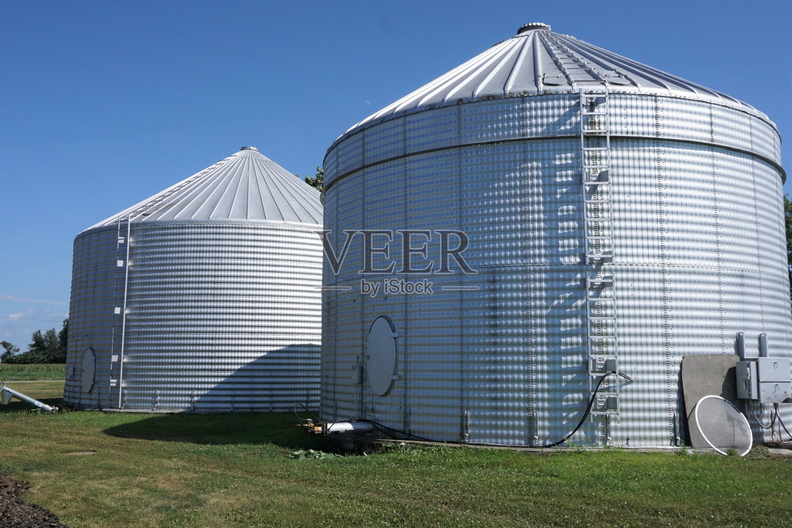 蓝色天空映衬着两个银色的筒仓照片摄影图片