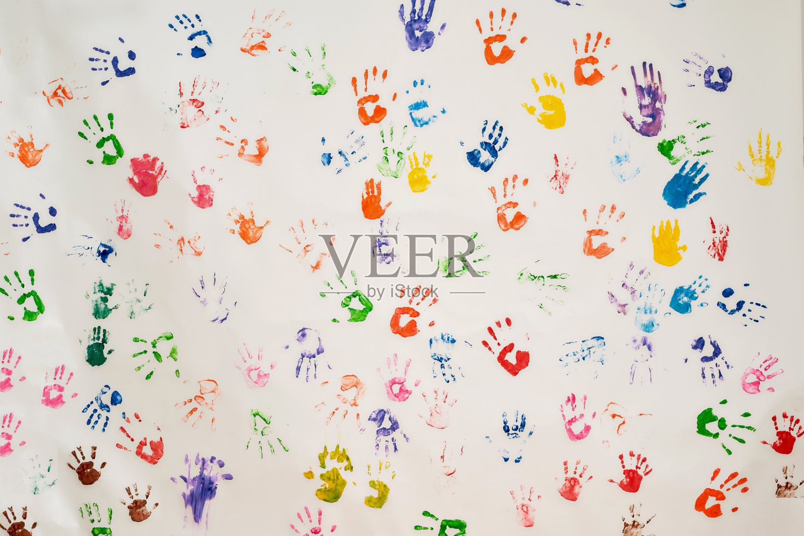 墙上有许多彩色手印的背景。童年的概念照片摄影图片