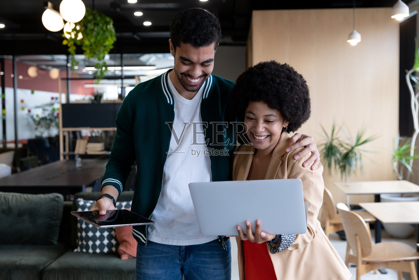 在办公室里使用笔记本电脑和平板电脑的快乐商人和女商人照片摄影图片