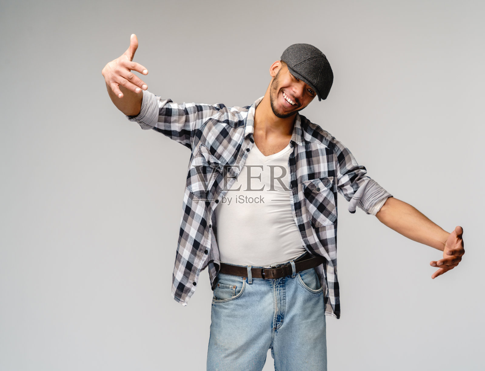 年轻英俊的非裔美国人在灰色背景看着相机微笑，张开双臂拥抱照片摄影图片