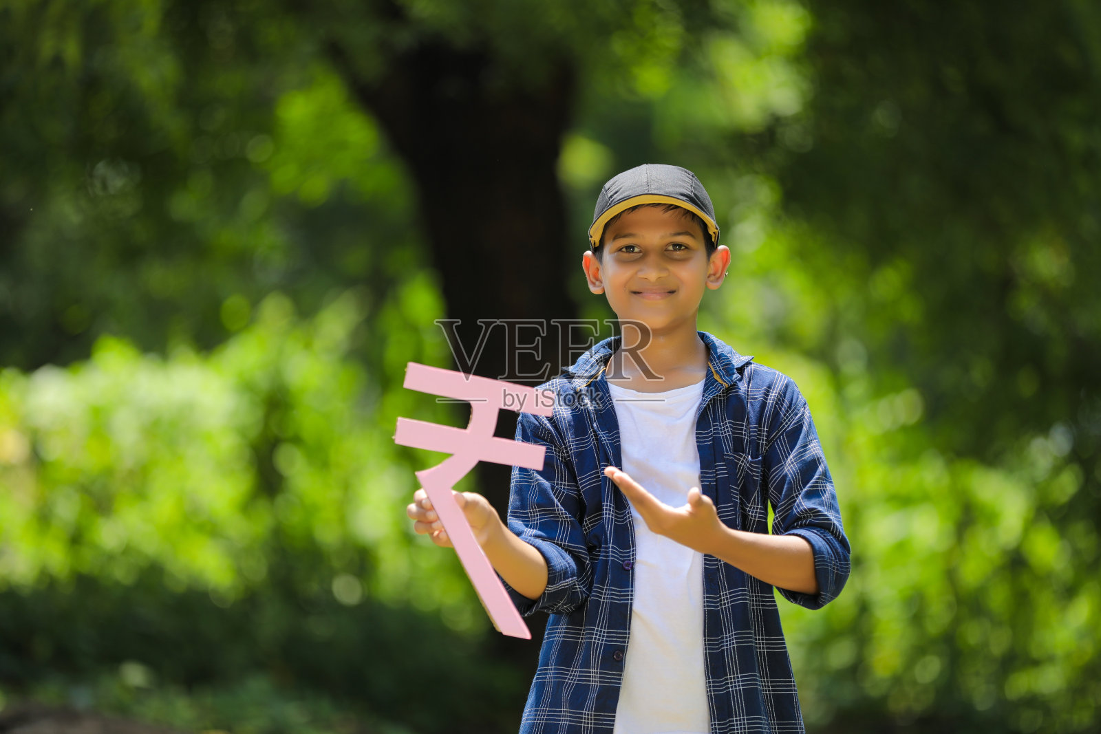 可爱的印度小孩手里拿着印度卢比符号，表情丰富照片摄影图片