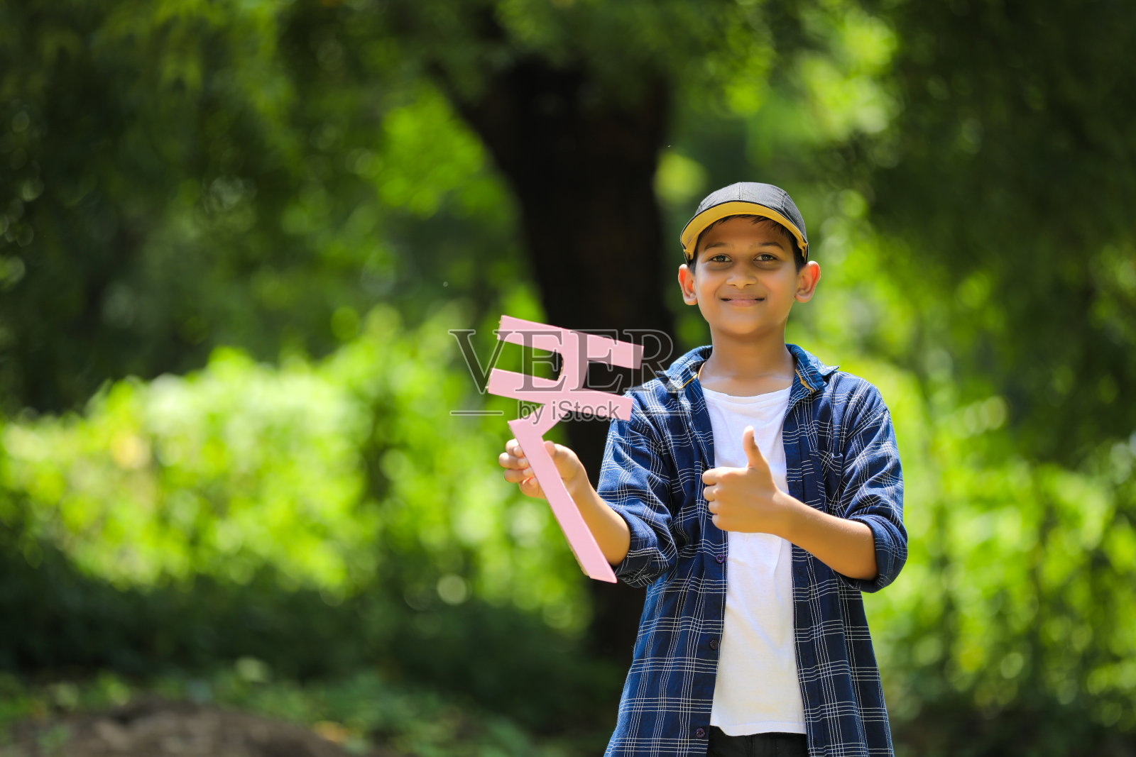 可爱的印度小孩手里拿着印度卢比符号，表情丰富照片摄影图片