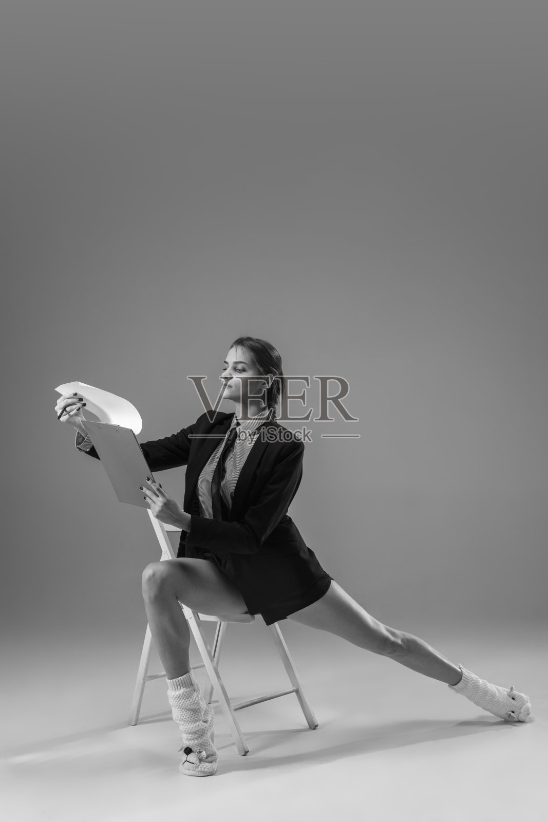 年轻、时尚、时髦的女性穿着夹克和袜子在家工作。保温期间的时尚是冠状病毒大流行的原因照片摄影图片