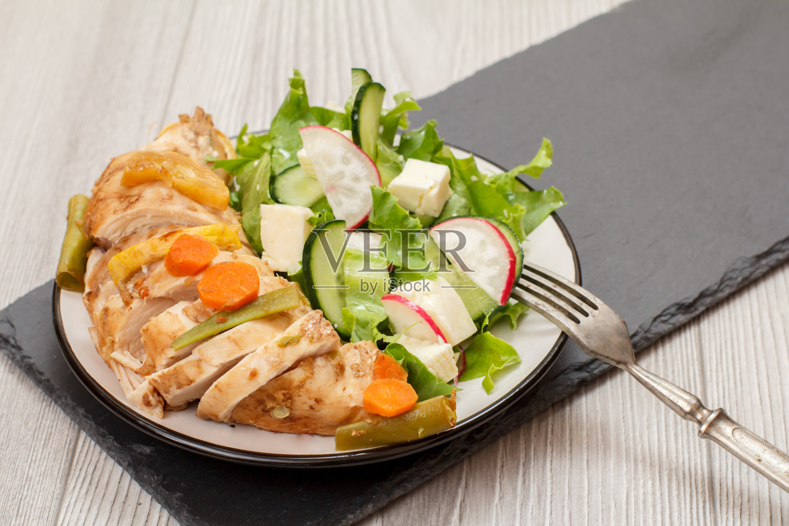 将肉、蔬菜沙拉、奶酪、黄瓜和萝卜放在石板上。照片摄影图片