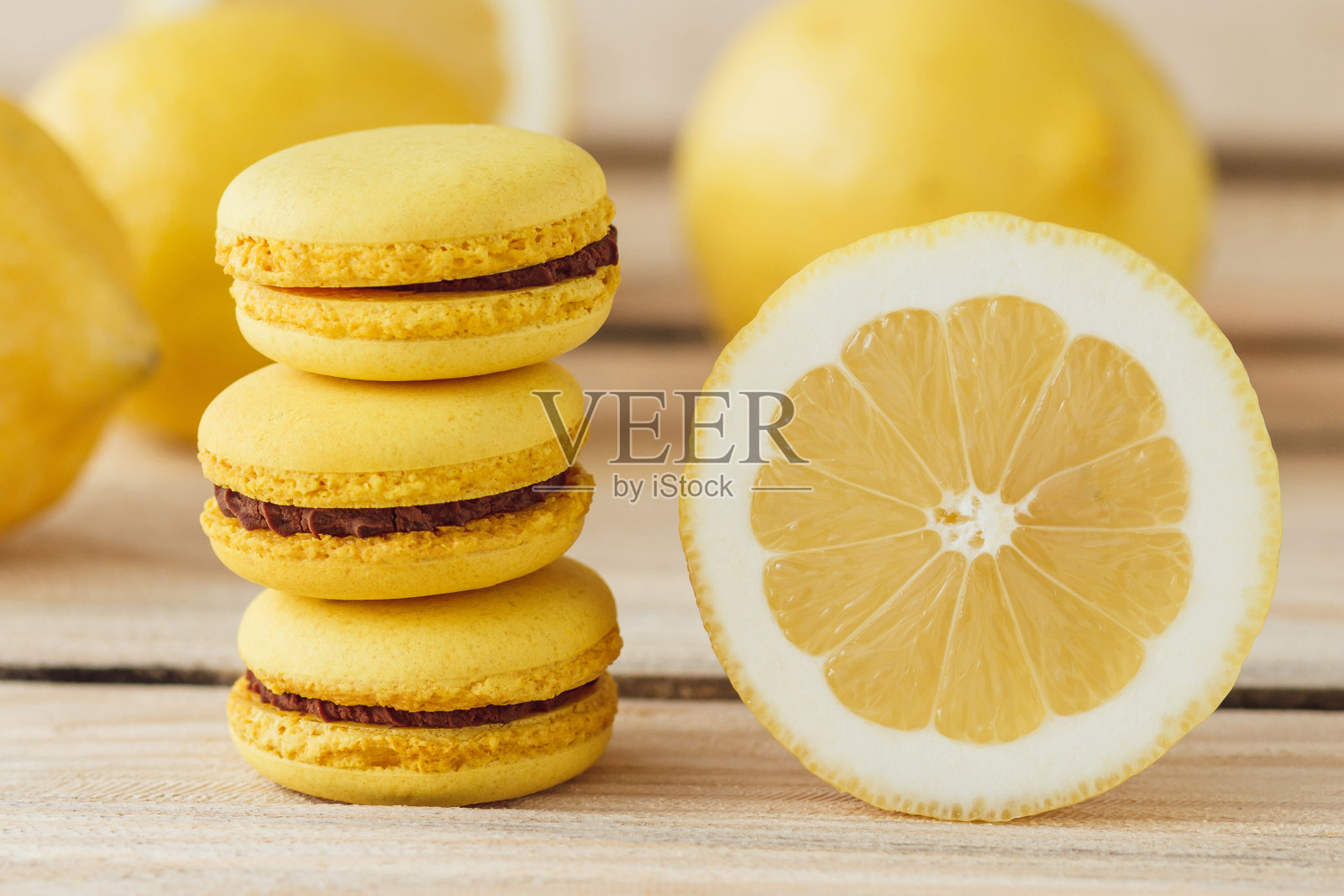 黄色的法式马卡龙和柠檬在木板上照片摄影图片