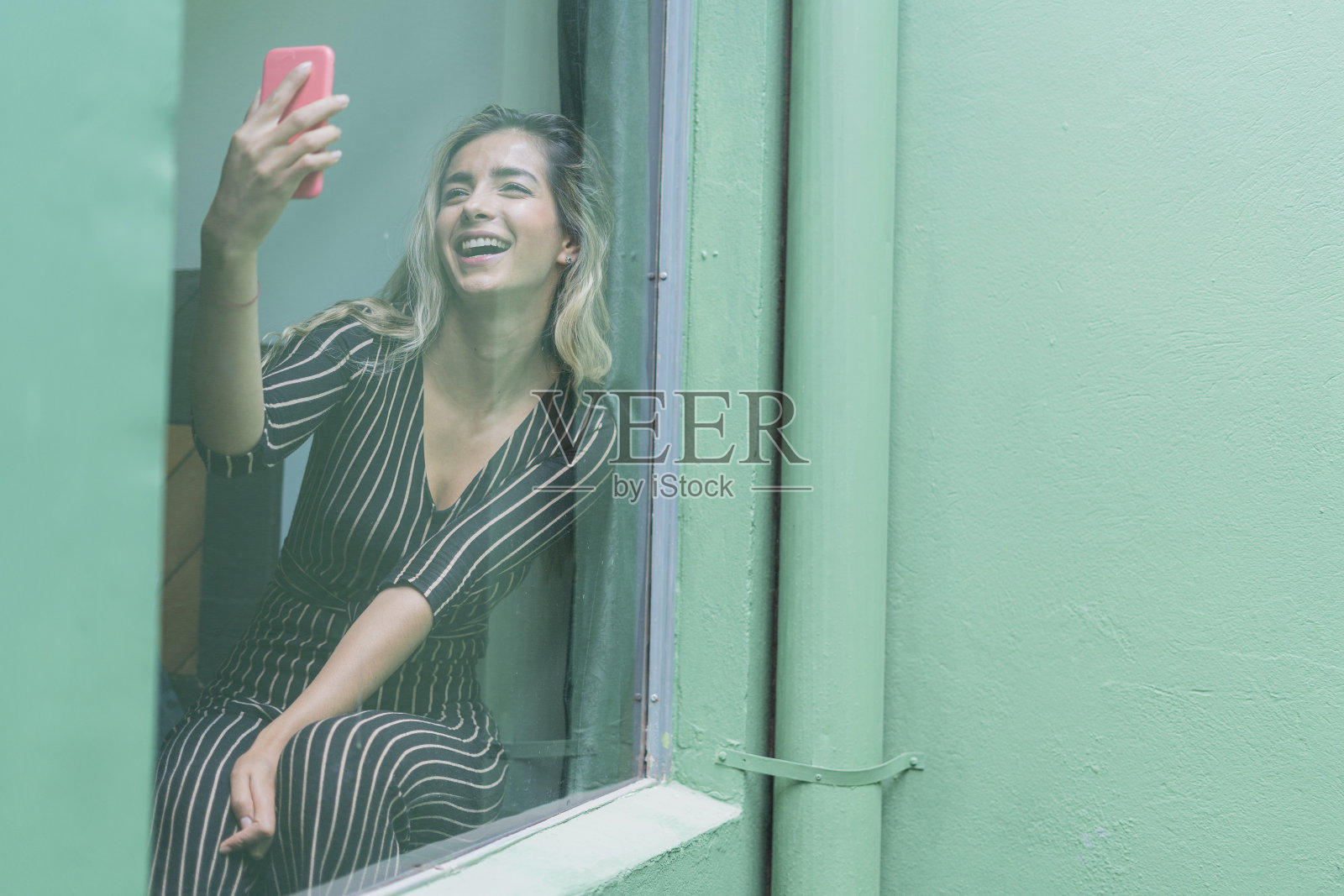 漂亮女人用窗边的手机打视频电话照片摄影图片