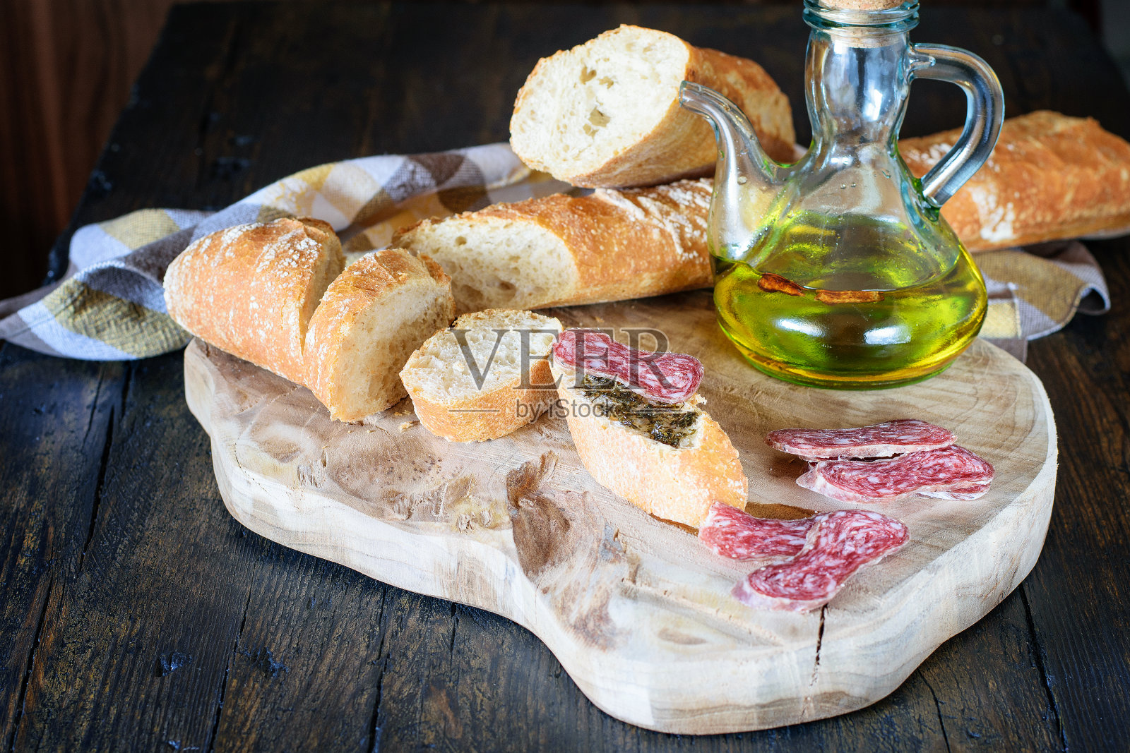 几片西班牙香肠，白面包和橄榄油放在天然的厨房木板上。一份涂了油的面包三明治和一份猪油。地中海健康食品。照片摄影图片
