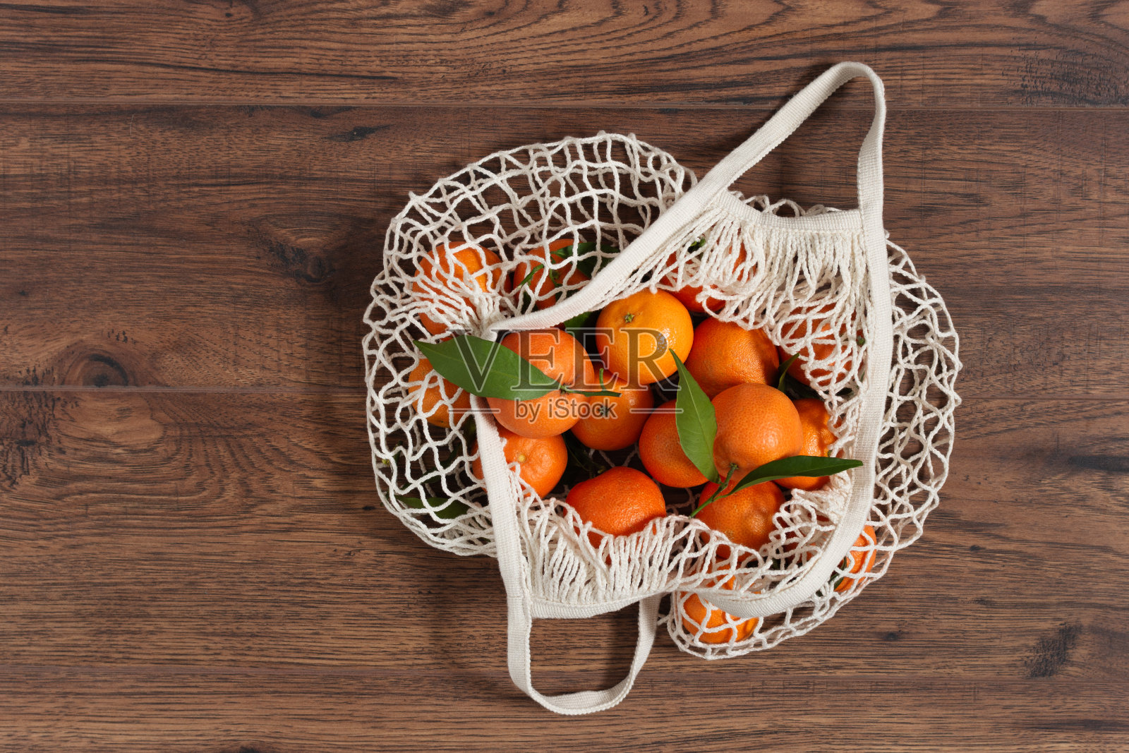 橘子在网眼购物袋顶视图上的木制背景。照片摄影图片