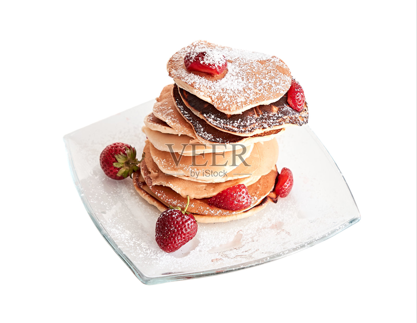 洒上糖粉的美味煎饼放在玻璃盘子里。素食早餐配草莓。健康食品。孤立在白色背景上。照片摄影图片