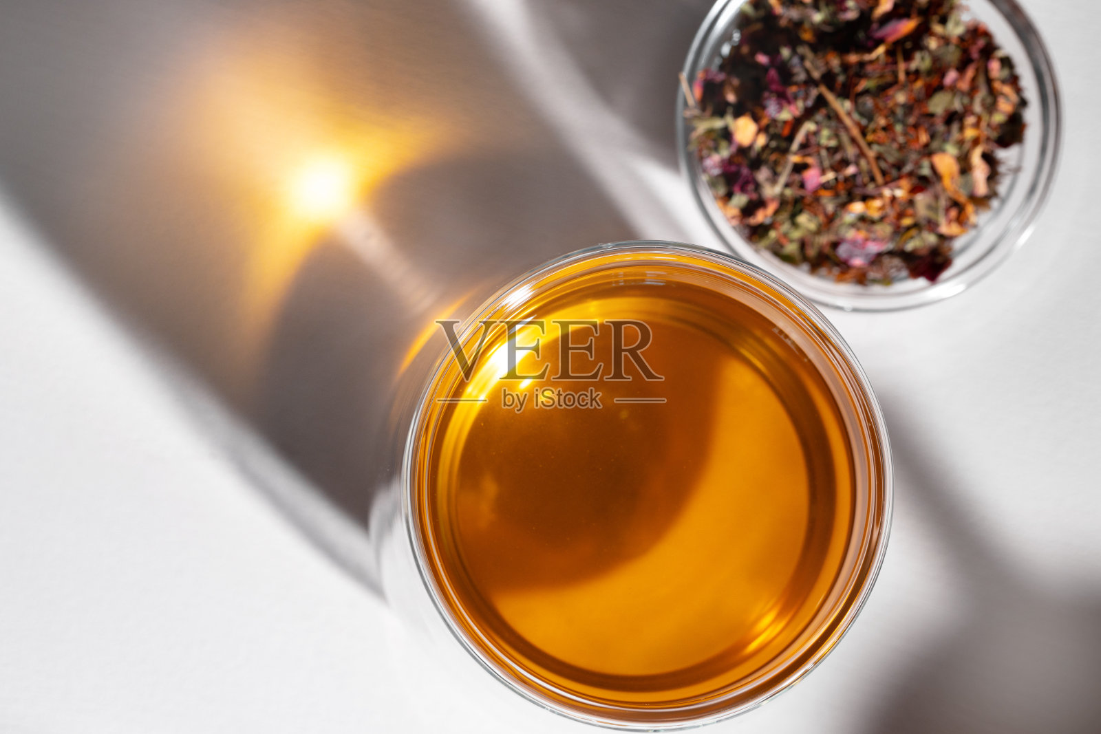 白色的桌子上放着一杯茶和干茶叶照片摄影图片