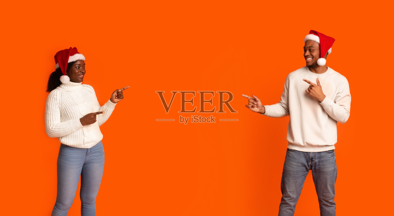 圣诞促销。幸福的黑人夫妇指着中间的拷贝空间照片摄影图片