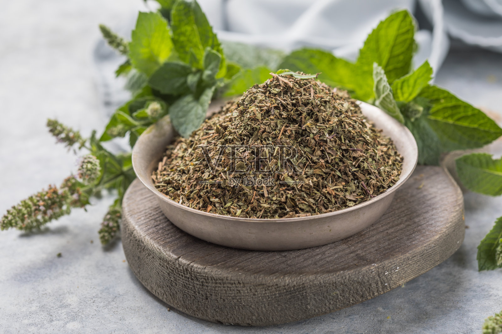 新鲜的绿薄荷叶和干薄荷叶放在碗里，放在质朴的桌子上。干香料的概念照片摄影图片