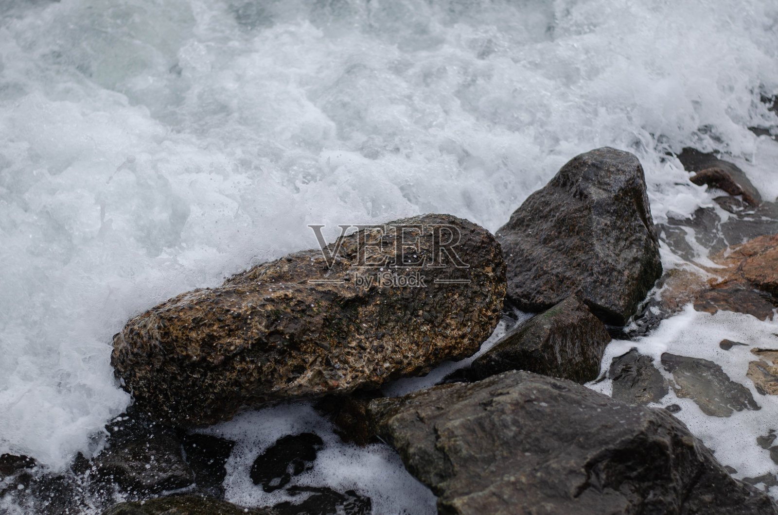海边的石头。海浪覆盖着石头。石头与藻类。照片摄影图片