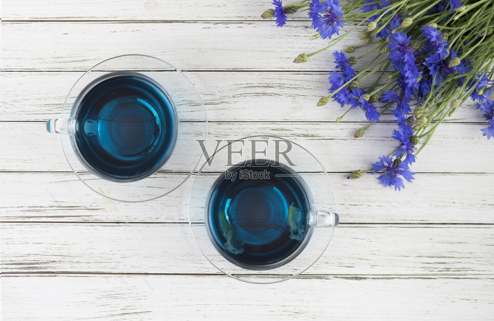几杯蝴蝶豌豆茶安珊，白木背景上的阴蒂。带着一束蓝色的花。平躺照片摄影图片
