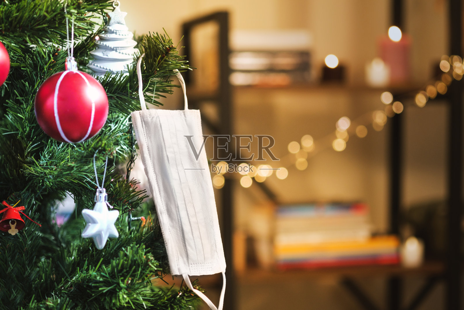 圣诞树上挂着圣诞装饰品和医用口罩。照片摄影图片