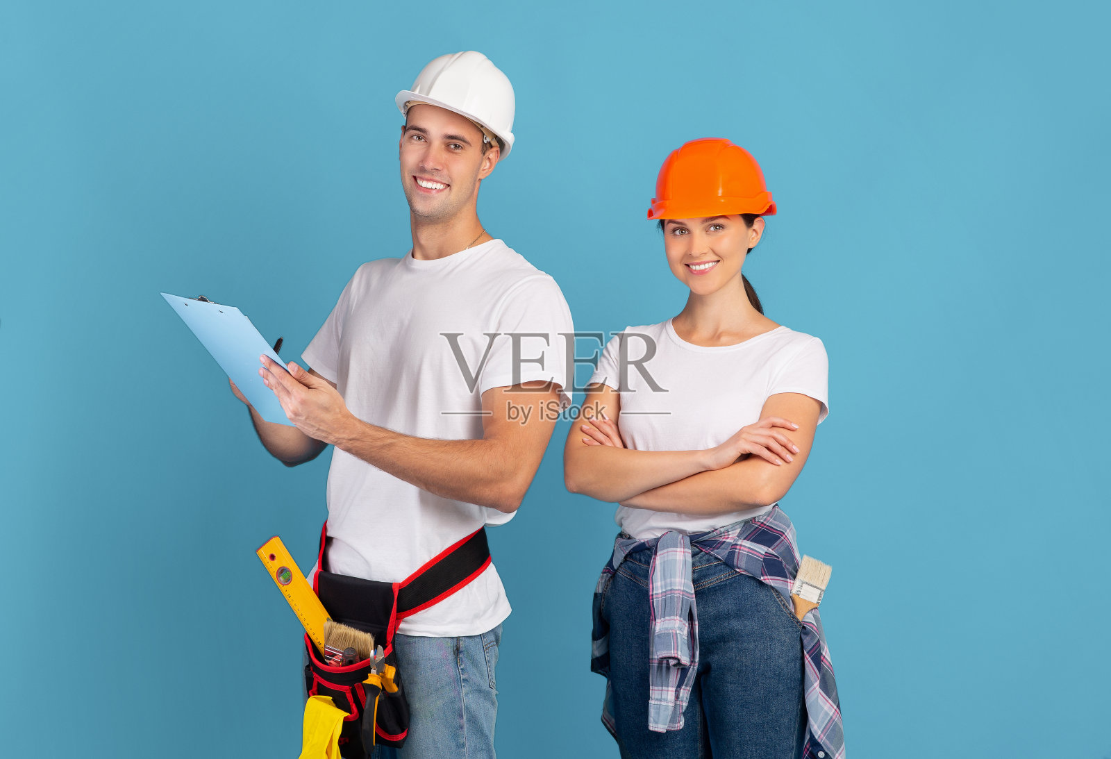 维修预算计划。男人和女人的肖像修理大师戴着头盔照片摄影图片