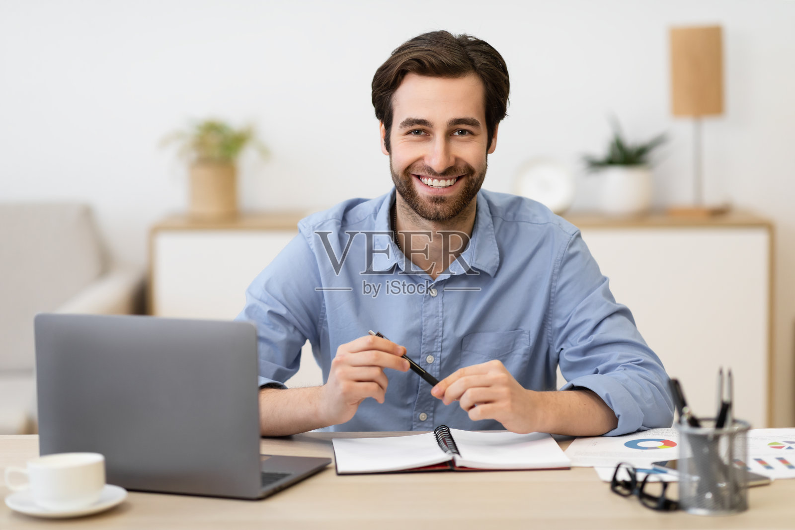 快乐的商人在办公室摆姿势坐在笔记本电脑前照片摄影图片