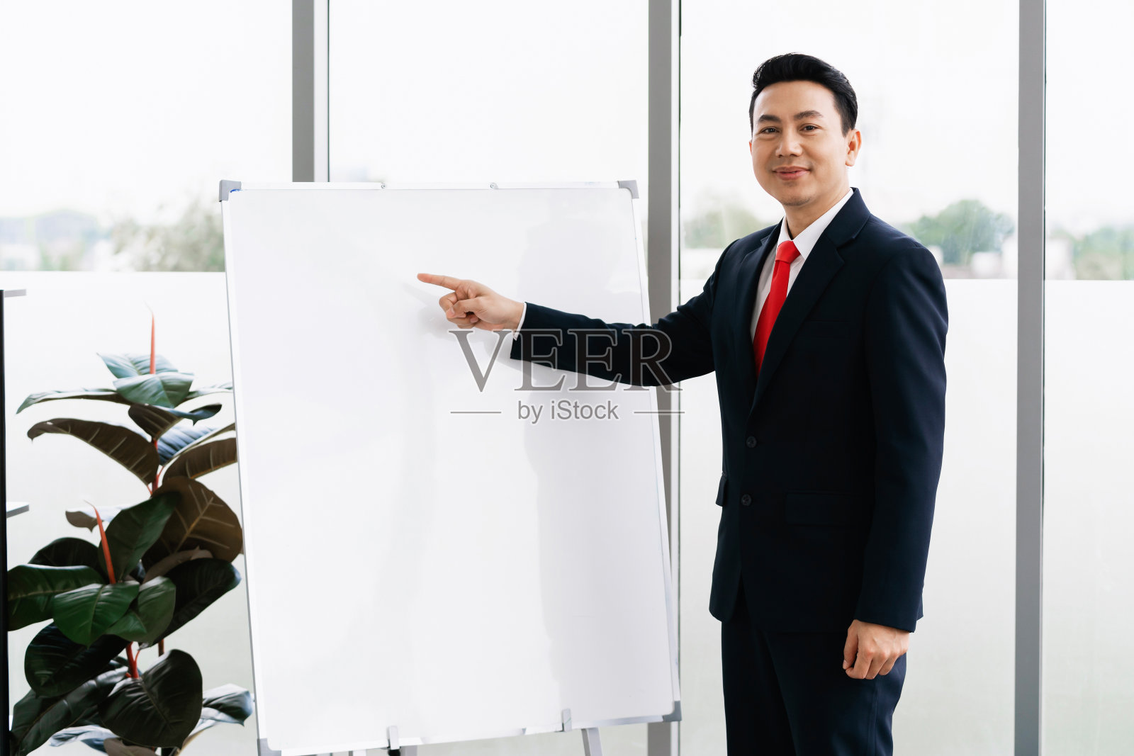 商人站在办公室指着白板开会照片摄影图片