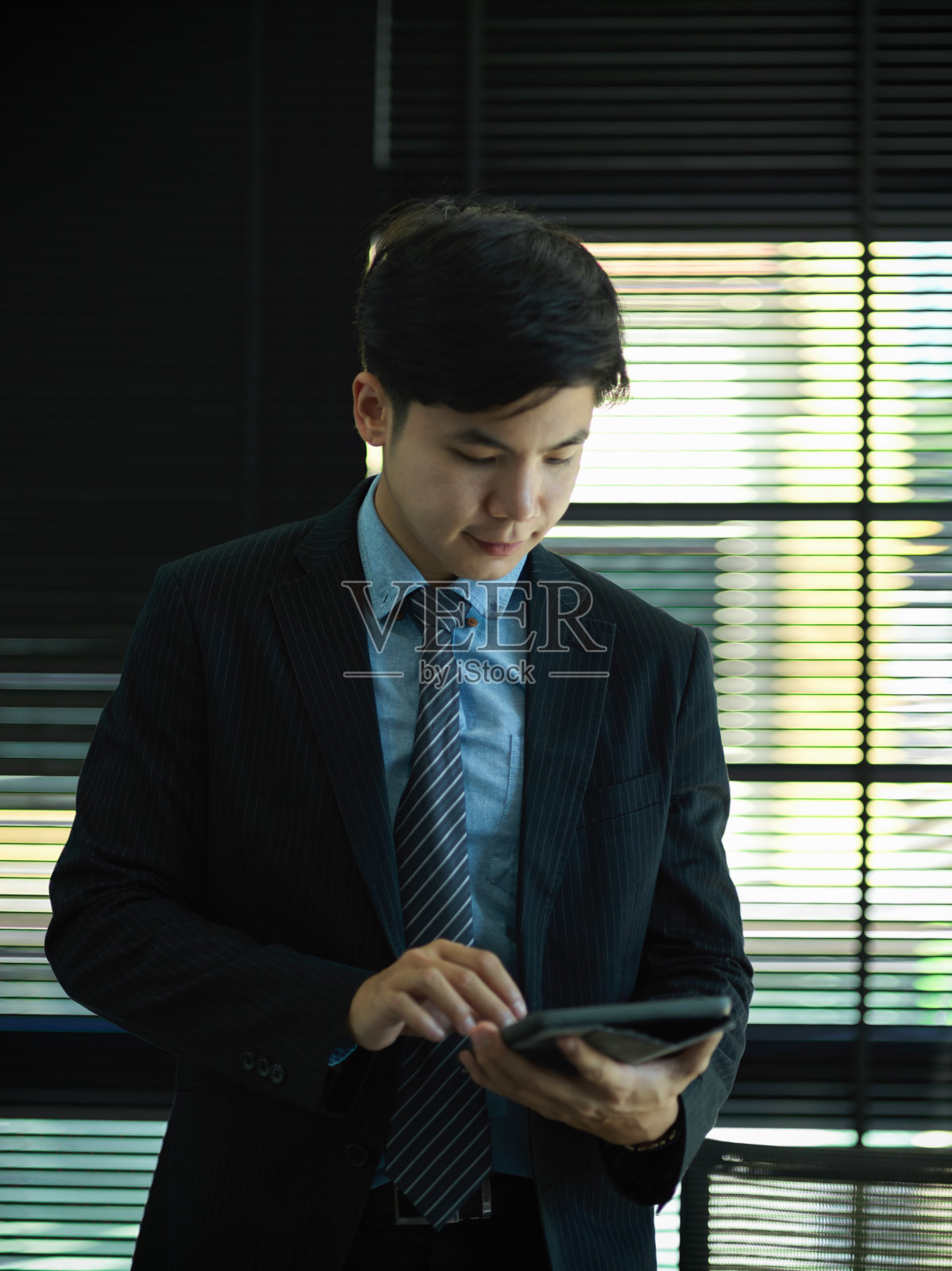 商人站在办公室里看数字平板电脑上的信息照片摄影图片