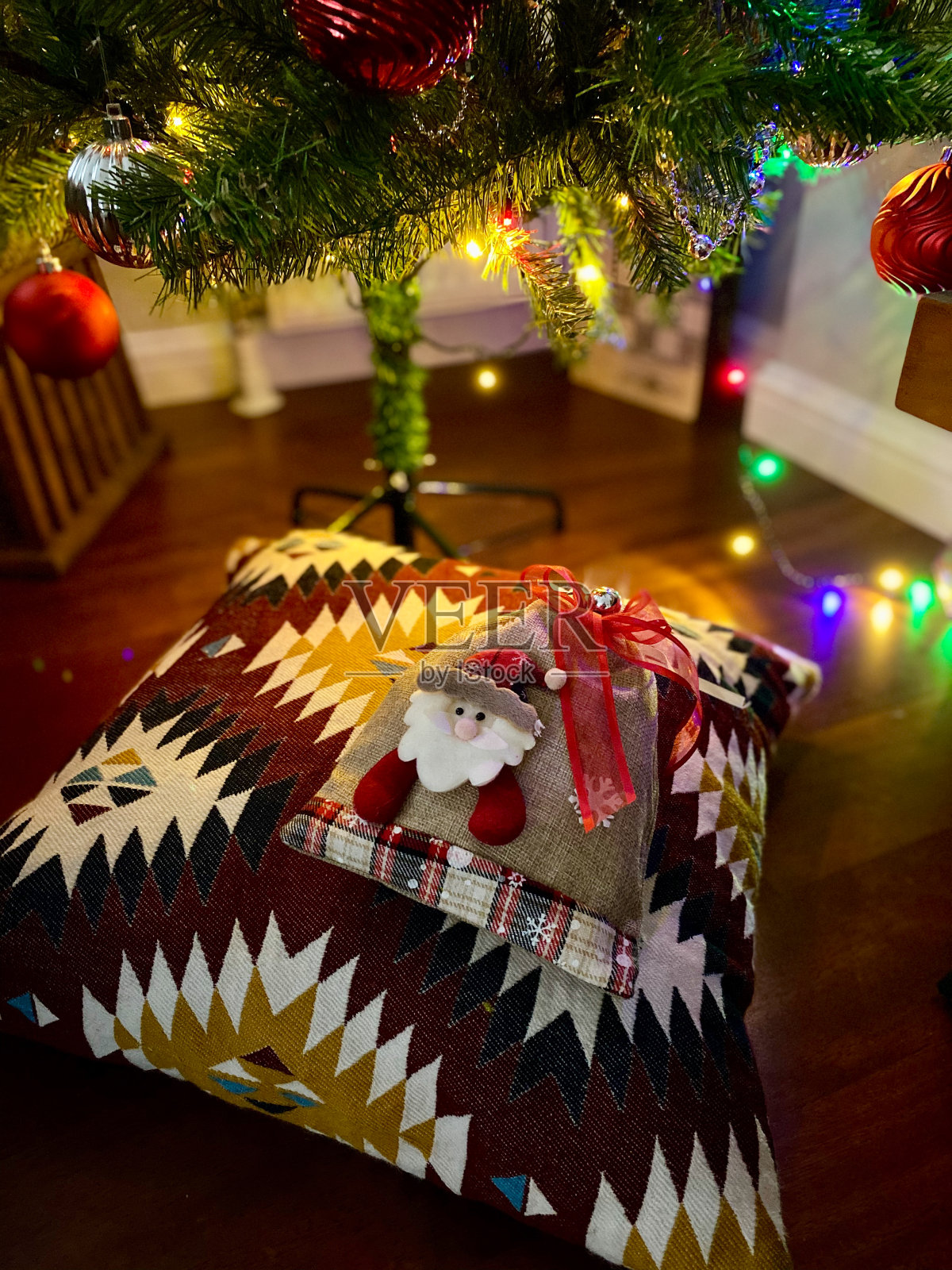 圣诞礼物:圣诞树下的枕头和圣诞老人图案。彩色Led灯。照片摄影图片