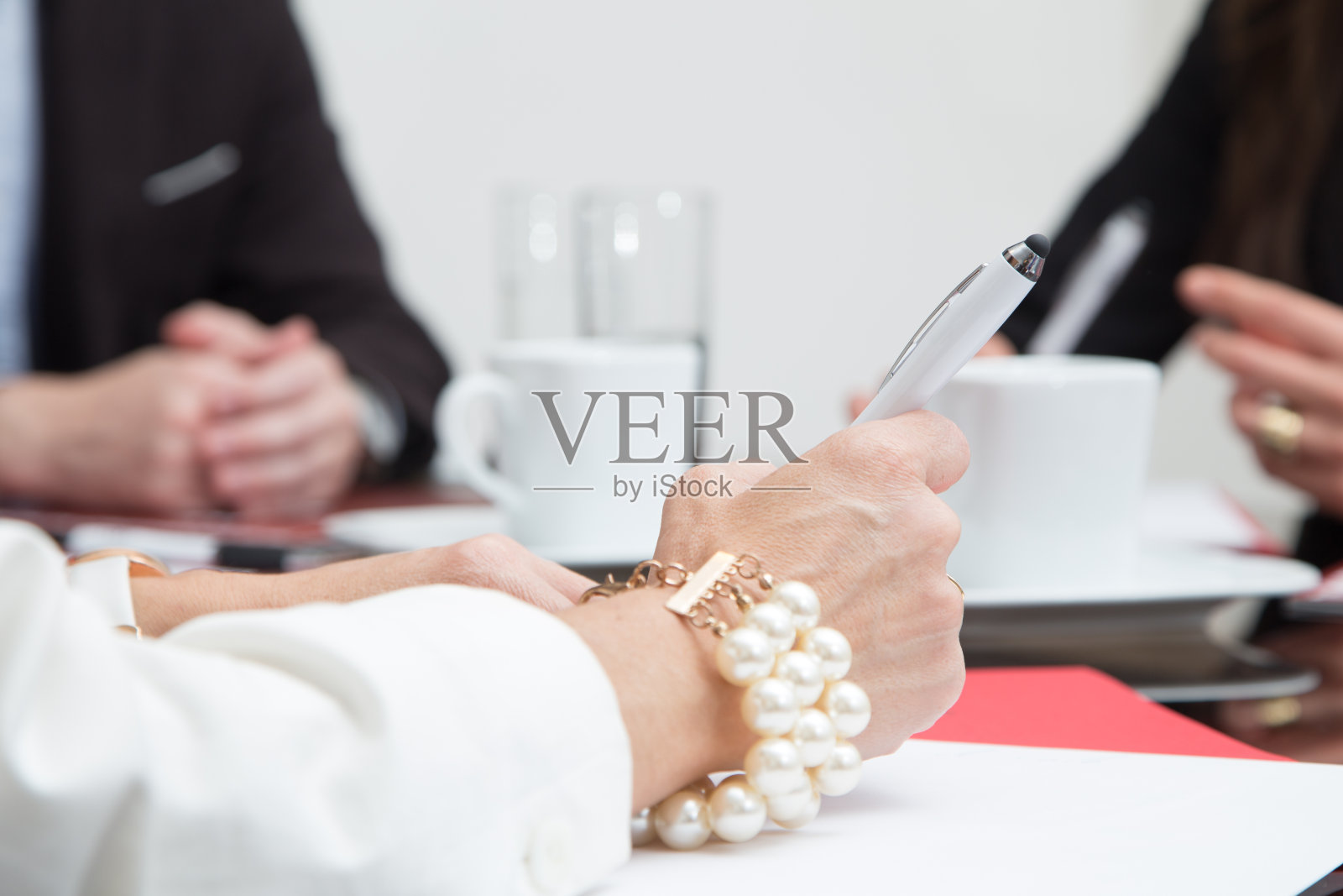 一位女士在办公室里开会时戴着一个非常优雅的手镯的手照片摄影图片