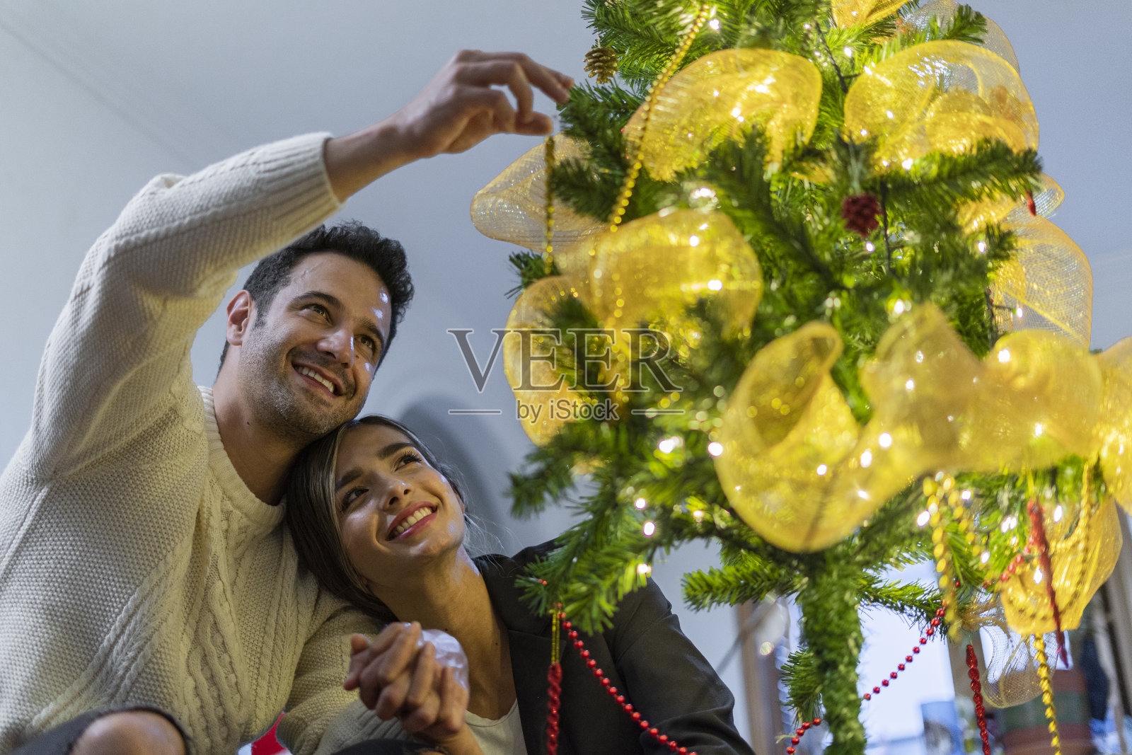 年轻夫妇喜欢在家里装饰和组装他们的圣诞树照片摄影图片